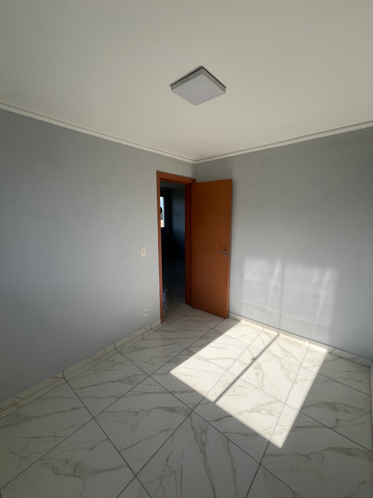 Quarto com porta de madeira e piso claro